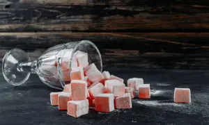 Un verre renversé d'où tombent des cubes de loukoum roses saupoudrés de sucre glace.