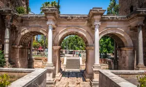 Łuk Hadriana, brama do **Antalya stare miasto**. Kamienne łuki i kolumny, w tle schody i zielone drzewa.