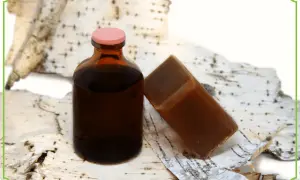 Brązowa buteleczka z płynem i kostka mydła na korze brzozy. Dziegieć co to? To naturalny produkt o wielu zastosowaniach.