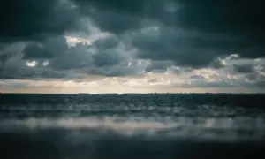 Mroczne chmury zapowiadają nadchodzący szkwał. Woda faluje, a horyzont ginie w zamgleniu.