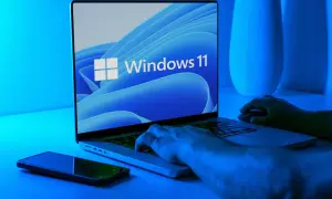 Ręce na klawiaturze laptopa z logo Windows 11. Dowiedz się, jak wejść do BIOS-u, by dostosować ustawienia.