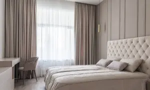 Elegancka sypialnia z dużym łóżkiem i zasłonami, które mogą być zawieszone na karniszach lub szynach.