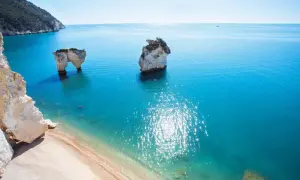 Faraglioni iconici sulla costa del Gargano, bagnati da un mare cristallino e soleggiato.