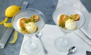 Två glas med citronsorbet, maräng och biscotti. En perfekt limoncello dessert för en solig dag.