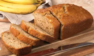 Pokrojony, złocisty chlebek bananowy, obok pęk dojrzałych bananów. Idealny na najprostszy chlebek bananowy.