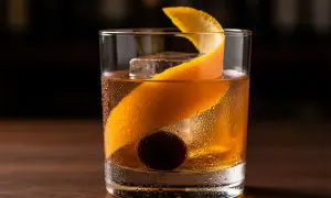 En old fashioned-drink med is, apelsinskal och körsbär.