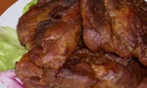 Soczysta karkówka pieczona na talerzu z sałatą.