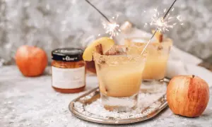 Dwa drinki z whisky i sokiem jabłkowym, ozdobione plasterkiem jabłka i cynamonem, z zimnymi ogniami.