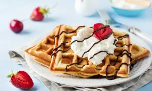 Pyszne gofry z bitą śmietaną i truskawkami, polane czekoladą. Idealne na śniadanie, gdy szukasz przepisów na dietę bezglutenową.