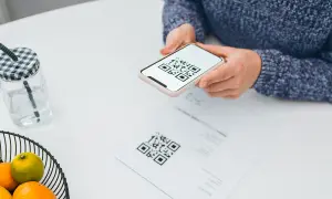 Une personne scanne un QR code sur un document avec son téléphone, peut-être pour activer une carte eSIM Bouygues.