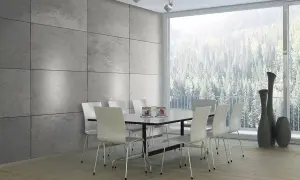 Esszimmer mit moderner Beton Optik Wandverkleidung, weißem Tisch und Stühlen, sowie einem Panoramafenster mit Blick auf einen Wald.