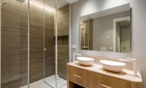 Baños pequeños con encanto: ducha con paredes de madera acanalada y tocador de madera con dos lavabos blancos.