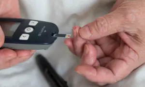 Osoba z **stanem przedcukrzycowym** mierzy poziom glukozy we krwi glukometrem.