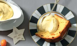 Una fetta di panettone con abbondante crema al mascarpone, servita su un piatto decorato. Un'idea golosa per le feste.