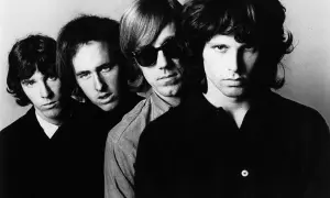 Członkowie The Doors, czwórka młodych mężczyzn z burzą włosów, patrzą w obiektyw. Jeden z nich ma okulary przeciwsłoneczne.