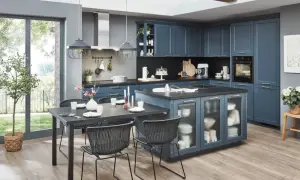 Cocinas con isla en azul marino, con encimera oscura, mesa de comedor y sillas negras. Ventanal grande con vistas al jardín.