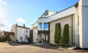 Nowoczesny budynek hotelu Santana Białystok z podjazdem z kostki brukowej i zielenią.