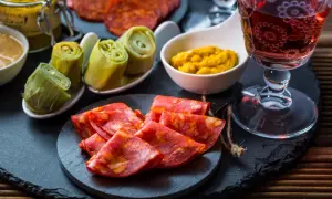 Leckere Tapas Ideen: Chorizo, eingelegte Artischocken und Senf mit einem Glas Rotwein.