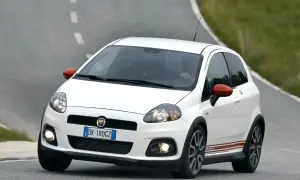 Biały Fiat Punto Abarth z czerwonymi lusterkami i paskami na boku, jadący po krętej drodze.