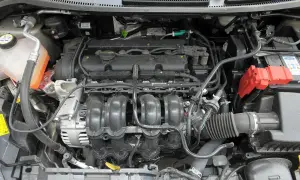 Silnik Ford Fiesta 2011 z widocznym kolektorem dolotowym, alternatorem i akumulatorem.