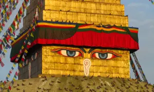 Złota stupa z oczami Buddy, ozdobiona kolorowymi flagami modlitewnymi. Warto odwiedzić takie miejsca święte w buddyzmie w Nepalu i Indiach.