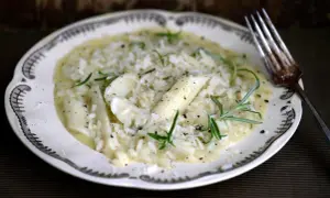 Krämig risotto med sparris och rosmarin, perfekt för ett svamprisotto recept. Serveras på en vacker tallrik med en gaffel.