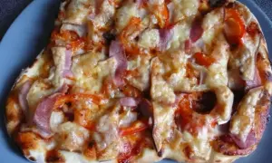 Pyszna pizza z szynką, papryką i cebulą, zapieczona pod ciągnącym się serem. Idealna na szybki obiad.