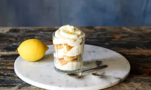 Un délicieux tiramisu aux agrumes, servi dans un verre, avec un citron frais à côté.