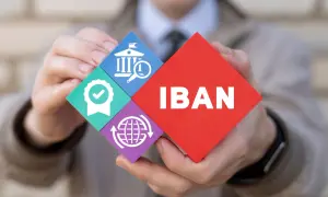 Ręce trzymają puzzle z napisem IBAN i ikonami: bank, pieczęć jakości, globalny zasięg.