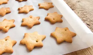 Gwiazdki z kruchego ciasta posypane cukrem, ułożone na papierze do pieczenia. Idealne do przechowywania po upieczeniu.