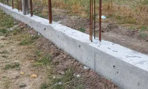 Solidna podmurówka ogrodzenia panelowego z wystającymi prętami zbrojeniowymi, gotowa na montaż.