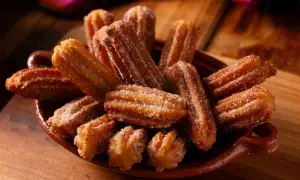 Un piatto colmo di churros dorati, cosparsi di zucchero. Una deliziosa churros ricetta da gustare.