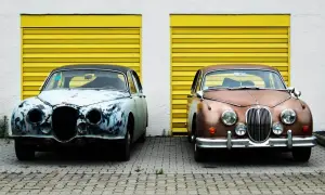 Zwei Oldtimer vor gelben Garagentoren. Einer ist stark verrostet, der andere glänzt. Überlegen Sie, ob auto selber lackieren kosten günstiger sind.