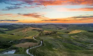 Die Toskana-Route schlängelt sich durch sanfte Hügel unter einem dramatischen Sonnenuntergang.