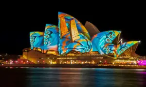 Sydney Opera House nocą, oświetlona kolorowymi projekcjami.