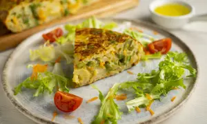 Pyszny omlet z piekarnika z fasolką szparagową i marchewką, podany z sałatką i pomidorkami.