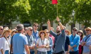 Ein Reiseleiter mit roter Fahne führt eine Gruppe bei kostenlosen Stadtführungen an.