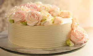 Tort udekorowany kremowymi różami w pastelowych kolorach.