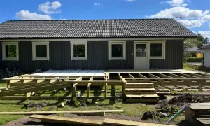 Grundarbete för att bygga veranda. Träkonstruktion och trappor på plats framför huset.