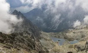 Widok na Tatry z mgłą, idealne miejsce na pierwsze górskie wędrówki. Szlak prowadzi w dół do malowniczych jezior.