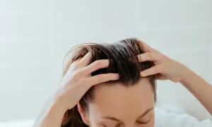 Mani che massaggiano il cuoio capelluto per alleviare la forfora secca.