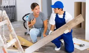 Un ouvrier montre une lame de parquet à une cliente. Ces travaux réalisés par le propriétaire sont déductibles.