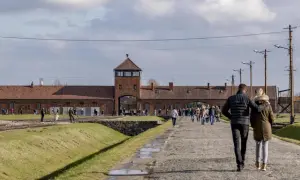 Spacer po terenie Państwowego Muzeum Auschwitz-Birkenau w Oświęcimiu. Ludzie zwiedzają teren dawnego obozu.