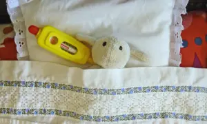 En mjuk kanin med feber och en gul termometer ligger i en säng. Barn ont i magen intervaller kan vara jobbigt.