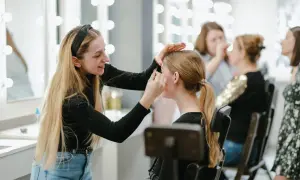 Uczestniczki szkoleń beauty ćwiczą makijaż przy lustrach z oświetleniem.