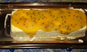 Gâteau glacé rectangulaire nappé d'un confit mangue passion aux graines visibles, sur un plateau doré.