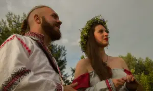 Para młoda w tradycyjnych strojach, symbolizująca żywą wiarę i tradycję przekazywaną w rodzinie.