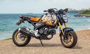 Niestandardowe malowanie baku motocykla z motywem płomieni i napisem "LET'S GO" na tle morza.
