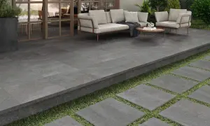 Terraza moderna con suelo de baldosas grises, ideal para pintar y renovar tu espacio exterior. Muebles de exterior y plantas verdes.