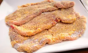 Mehrere panierte Schnitzel liegen auf einem weißen Teller, bereit für ein köstliches Schnitzel Rezept.